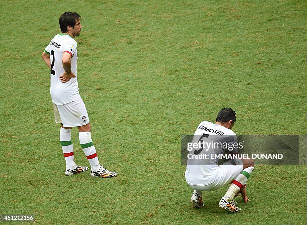 Iran's defender Khosro Heydari and Iran's defender Amir Hossein Sadeghi react after their team lost a Group F football match between...