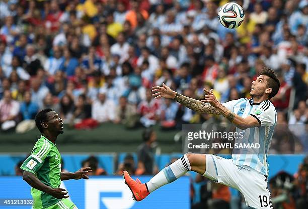 Nigeria's midfielder John Obi Mikel looks on as Argentina's midfielder Ricky Alvarez rises to head the ball during the Group F football match between...