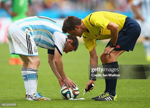 Lionel Messi of Argentina prepares to take a free kick as referee Nicola Rizzoli sprays a temporary line during the 2014 FIFA World Cup Brazil Group...