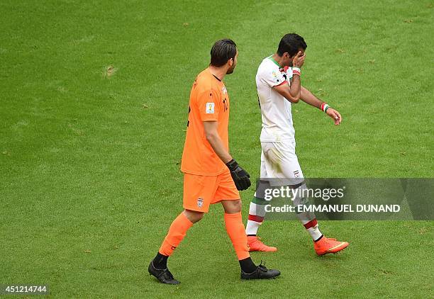 Iran's goalkeeper Alireza Haghighi walks with Iran's defender Mehrdad Pooladi after Bosnia-Herzegovina's midfielder Avdija Vrsajevic scored his...