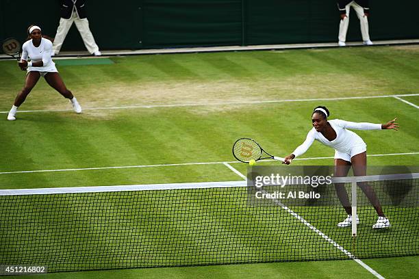 Venus Williams of the United States returns the ball as Serena Williams looks on during their Ladies Doubles first round match against Oksana...