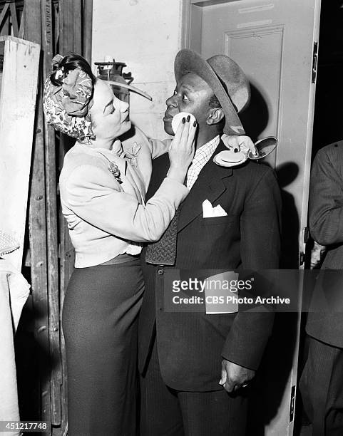 Singer Carmen Miranda applies make-up to surprised actor Eddie "Rochester" Anderson during a break in rehearsals for the CBS radio program "ELGIN...