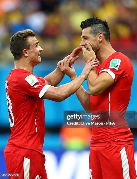 Xherdan Shaqiri of Switzerland speaks to Blerim Dzemaili as he is replaced during the 2014 FIFA World Cup Brazil Group E match between Honduras and...