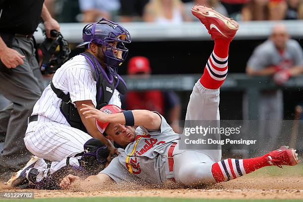 Mark Ellis of the St. Louis Cardinals slides home to score against catcher Wilin Rosario of the Colorado Rockies on a pinch hit double by Daniel...