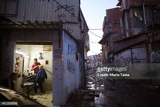 Man receives a haircut near the remains of demolished homes in the Metro Mangueira favela, located 750 meters from Maracana stadium, where Ecuador...
