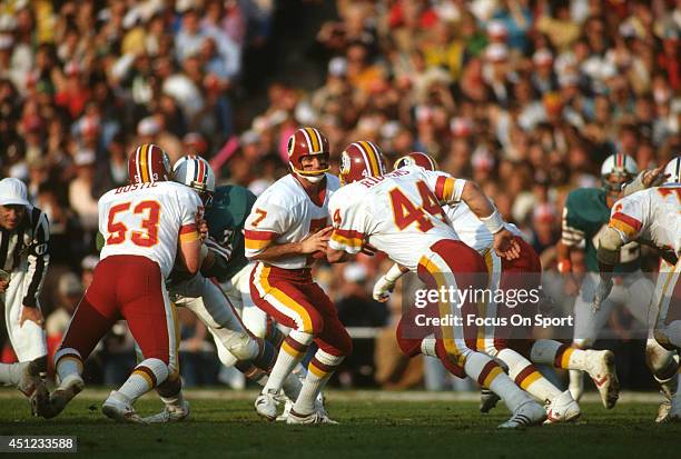 Joe Theismann of the Washington Redskins turns to hand the ball off to running back John Riggins against the Miami Dolphins during Super Bowl XVII on...