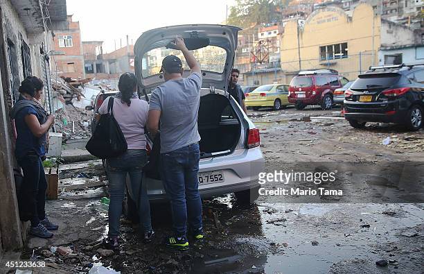 Mexican tourists attending the World Cup match park their car near the remains of demolished homes in the Metro Mangueira favela, located 750 meters...