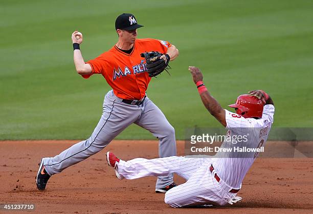 Ed Lucas of the Miami Marlins throws to first after missing the bag at second base, as Marlon Byrd of the Philadelphia Phillies slides in safe in the...