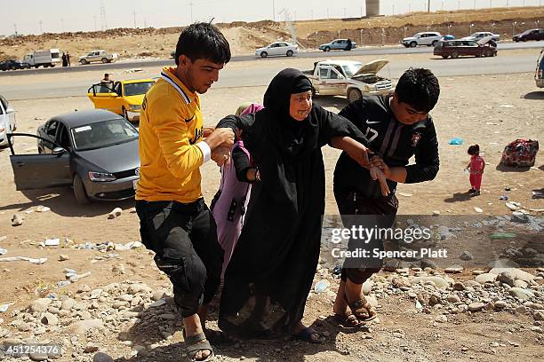 An elderly Iraqi woman is helped into a temporary displacement camp for Iraqis caught-up in the fighting in and around the city of Mosul on June 26,...