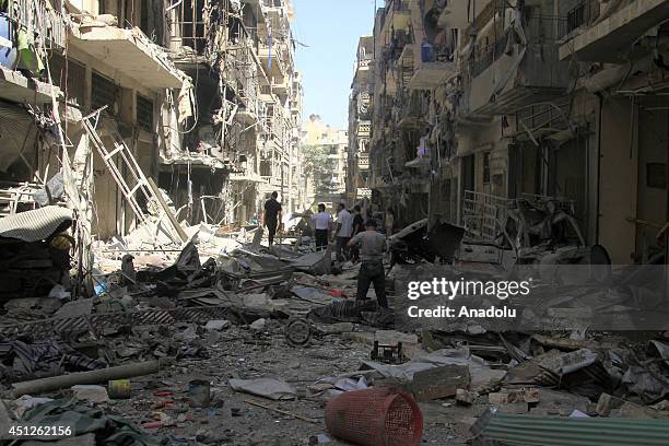 Syrians inspect the destroyed buildings following a Syrian government air strike in Aleppo, Syria, on June 26, 2014. At least 17 people including...