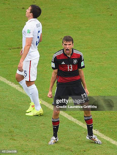 Thomas Mueller of Germany celebrates scoring his team's first goal as Matt Besler of the United States looks on during the 2014 FIFA World Cup Brazil...