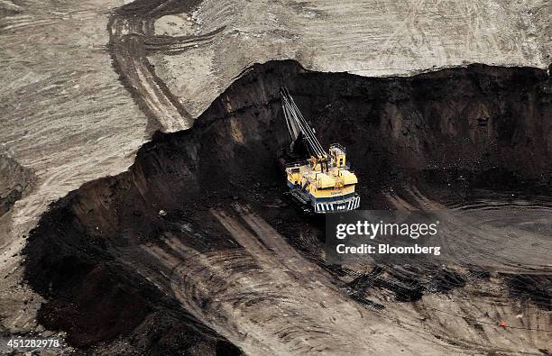 Machine works at the Suncor Energy Inc. Mine in this aerial photograph taken above the Athabasca Oil Sands near Fort McMurray, Alberta, Canada, on...