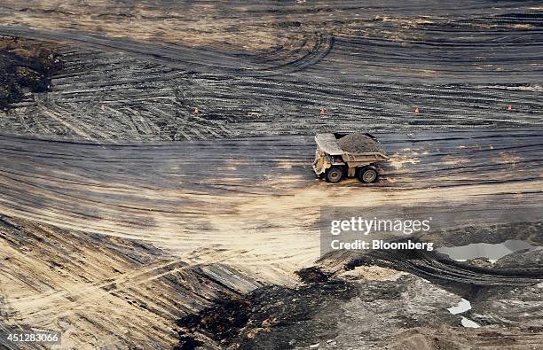 Truck drives through the Syncrude Canada Ltd. Mine in this aerial photograph taken above the Athabasca Oil Sands near Fort McMurray, Alberta, Canada,...