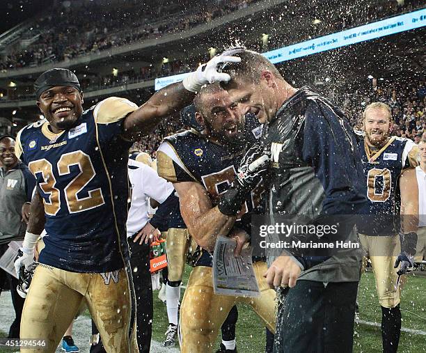Mike O'Shea, head coach of the Winnipeg Blue Bombers, gets congratulated by Nic Grigsby after he had a drink poured on top of him at the end of...