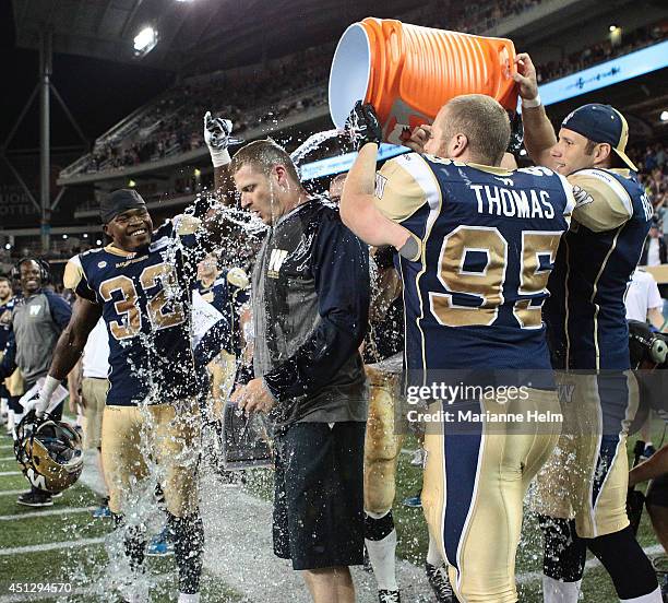 Mike O'Shea, head coach of the Winnipeg Blue Bombers, gets a drink poured on top of him at the end of second half action after they defeated the...