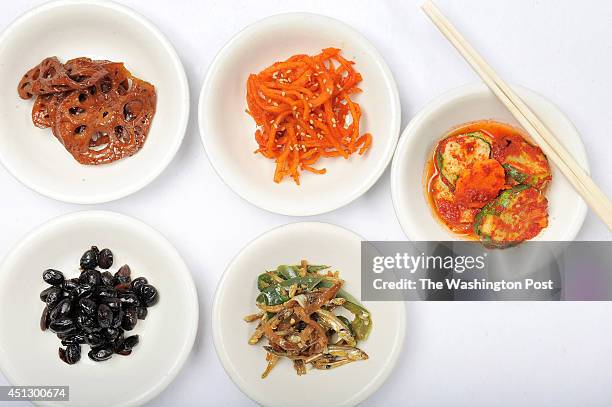 Food from top row, lotus root, sliced squid, cucumbers, and bottom row, braised beans, and anchovies are seen at Nak Won Restaurant on Wednesday June...