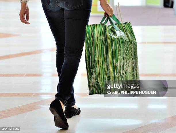 Woman carries a reusable carrier bag as she exits a shopping centre in Faches-Thumesnil, northern France, on June 27, 2014. A governmental amendment...
