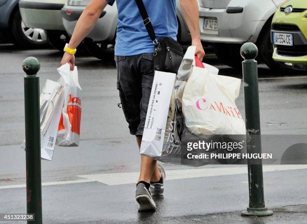Man carries several shopping bags as he exits a shopping centre in Faches-Thumesnil, northern France, on June 27, 2014. A governmental amendment...
