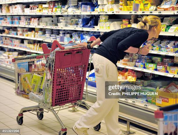 Woman looks at information on products as she buys groceries in an Auchan supermarket, a branch of the French international retail group Auchan, on...