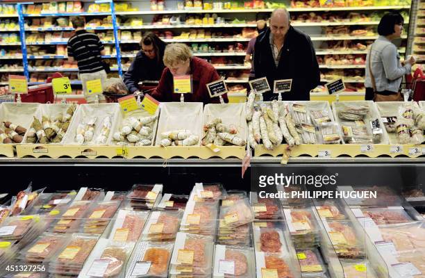 Consumerrs chooses products at the delicatessen section in an Auchan supermarket, a branch of the French international retail group Auchan, on June...