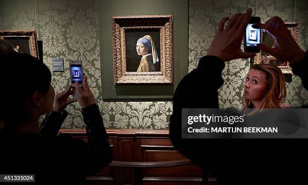 Visitors picture the painting of Johannes Vermeer's "Girl with the Pearl Earring", during a special evening opening in the renewed Mauritshuis museum...