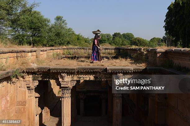 An elderly Indian woman carries a container of cowdung as she walks on the 15th century Ambapur Ni Vav or Stepwell at the village of Ambapur, some 30...