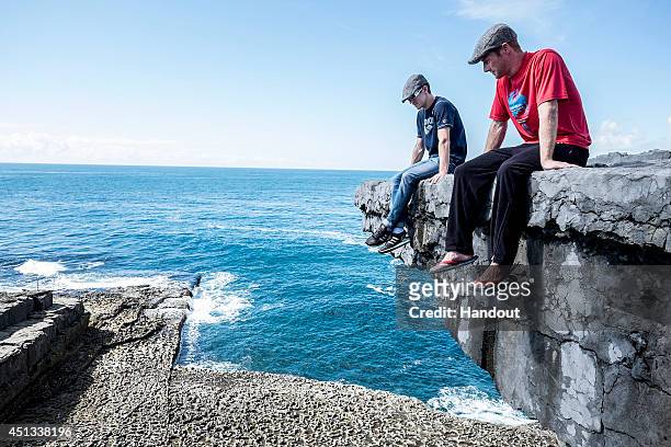 In this handout image provided by Red Bull, Mat Cowen of the UK and Andy Jones of the USA sit on the cliff edge at the Serpent's Lair during the...
