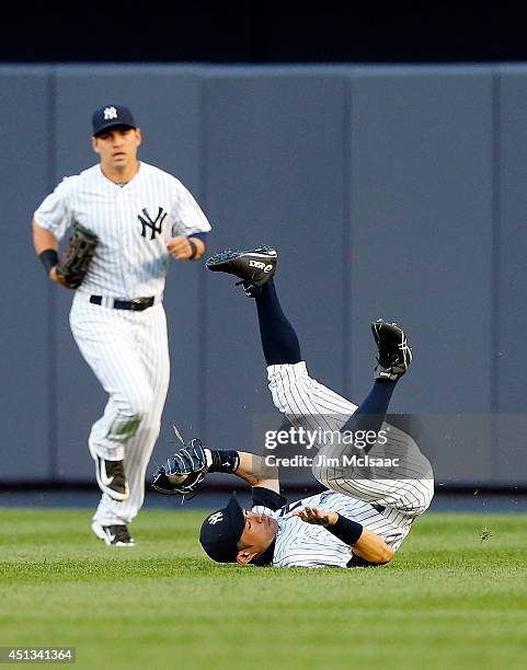 Ichiro Suzuki of the New York Yankees tumbles after making a catch on a ball hit by Stephen Drew of the Boston Red Sox to end the second inning as...