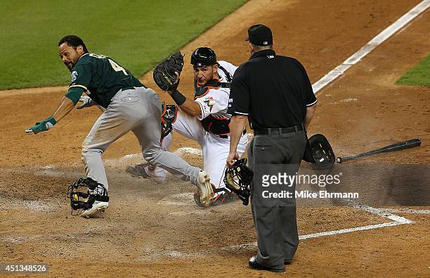 Coco Crisp of the Oakland Athletics slides into catcher Jeff Mathis of the Miami Marlins during a game at Marlins Park on June 27, 2014 in Miami,...