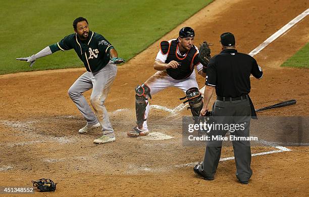 Coco Crisp of the Oakland Athletics slides into catcher Jeff Mathis of the Miami Marlins during a game at Marlins Park on June 27, 2014 in Miami,...