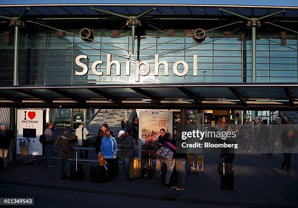 Passengers arrive and depart beneath a sign on the glass facade of Schiphol Airport, operated by the Schiphol Group, in Amsterdam, Netherlands, on...