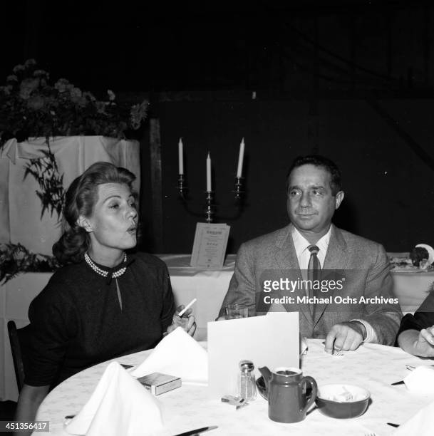 Actress Rita Hayworth sits with James Hill at a party in Los Angeles, California.