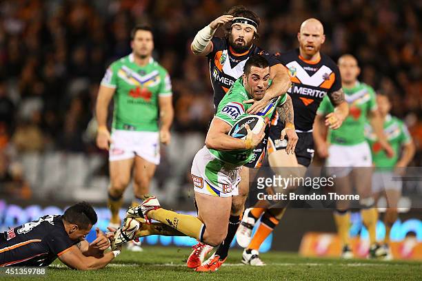 Paul Vaughan of the Raiders is tackled by Sauaso Sue and Aaron Woods of the Tigers during the round 16 NRL match between the Wests Tigers and the...