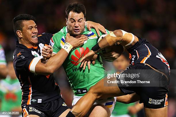 David Shillington of the Raiders is tackled by Sauaso Sue and Adam Blair of the Tigers during the round 16 NRL match between the Wests Tigers and the...