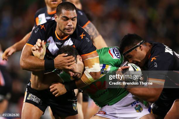 David Shillington of the Raiders is tackled by Adam Blair and Ava Seumanufagai of the Tigers during the round 16 NRL match between the Wests Tigers...