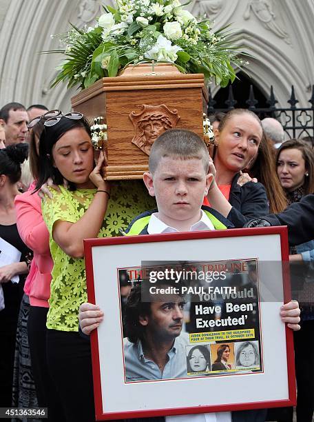 Padraig McKernan, aged 10, great nephew of Gerry Conlon, carries a framed newspaper headline in front of the coffin of Gerry Conlon, as it is carried...