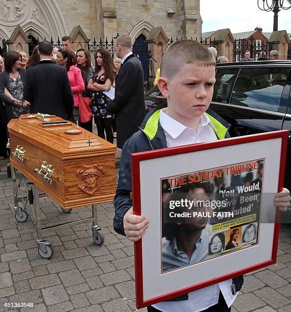 Padraig McKernan, aged 10, great nephew of Gerry Conlon, carries a framed newspaper headline in front of the coffin of Gerry Conlon, as it leaves St...