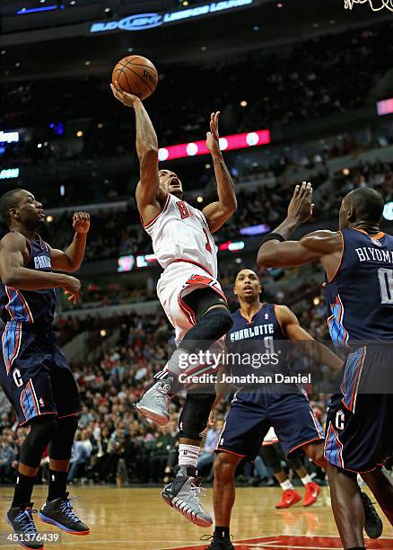 Derrick Rose of the Chicago Bulls shoots over Bismack Biyombo of the Charlotte Bobcats at the United Center on November 18, 2013 in Chicago,...