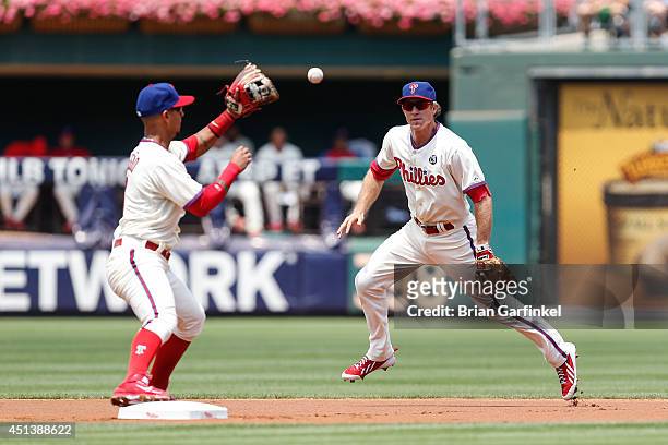 Chase Utley of the Philadelphia Phillies tosses the ball to Ronny Cedeno to turn a double play in the first inning of the first game of a...