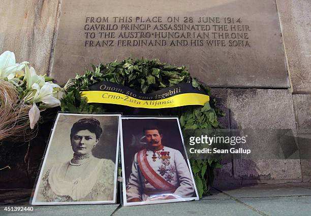 Portraits of Austrian Archduke Franz Ferdinand and his wife, Duchess Sophie, stand with a wreath under a plaque marking the spot where they were...