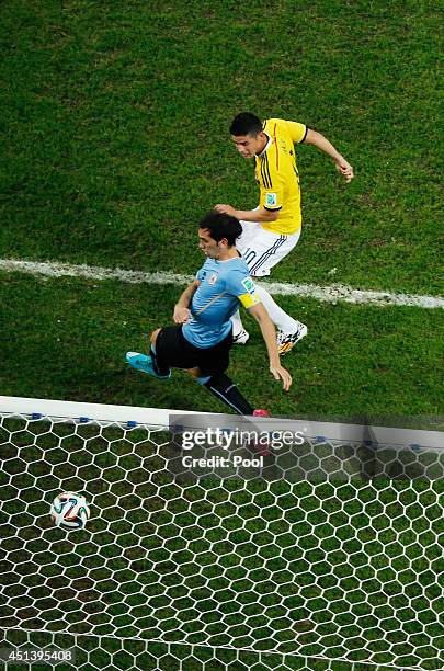 James Rodriguez of Colombia scores his team's second goal and his second of the game past Diego Godin of Uruguay during the 2014 FIFA World Cup...