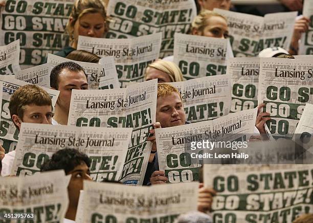 Michigan State Spartans fans read the Go State news paper as the visitors from the Columbia Lions are introduced prior to the start of the game at...