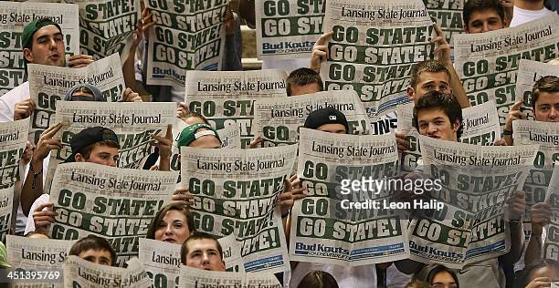 Michigan State Spartans fans read the Go State newspaper as the visitors from the Columbia Lions are introduced prior to the start of the game at the...