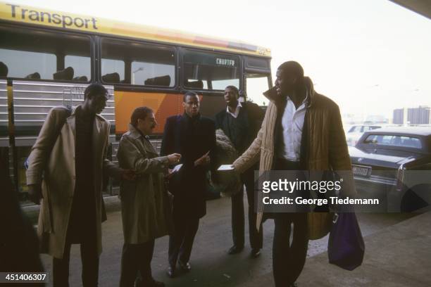View of Los Angeles Lakers Michael Cooper, trainer Gary Vitti, Byron Scott, Magic Johnson, and Mike McGee exiting bus into airport during road trip....