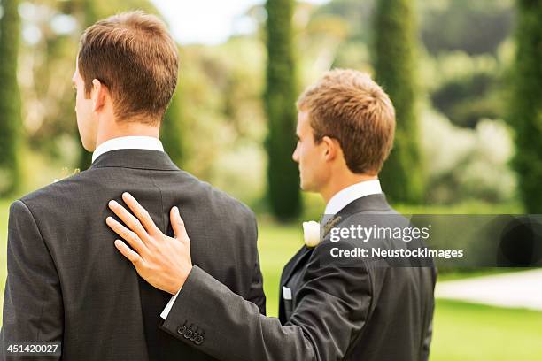 best man standing with hand on groom's back - best man stock pictures, royalty-free photos & images