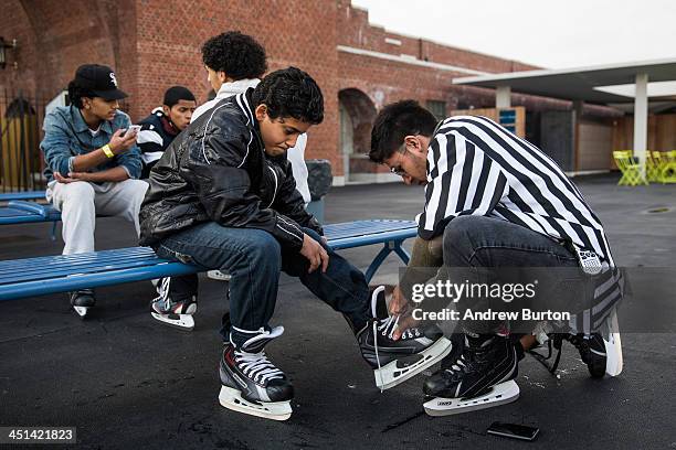 Ricardo Hernandez , a supervistor at the Ice Rink at McCarren Pool, helps tie the ice skates of a boy, on November 22, 2013 in the Green Point...