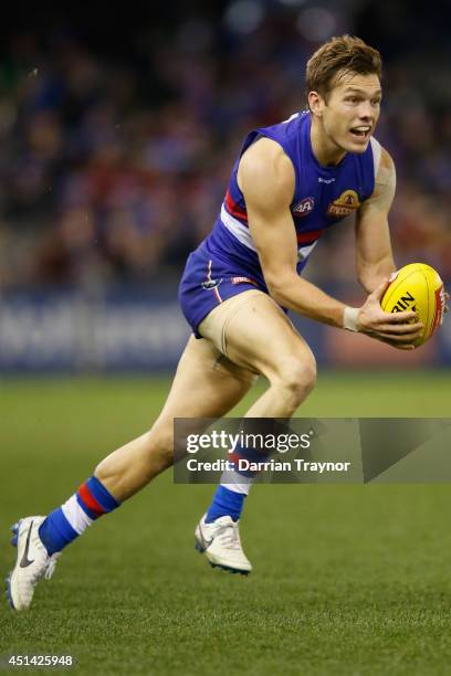 Shaun Higgins of the Bulldogs handballs during the round 15 AFL match between the Western Bulldogs and the Melbourne Demons at Etihad Stadium on June...