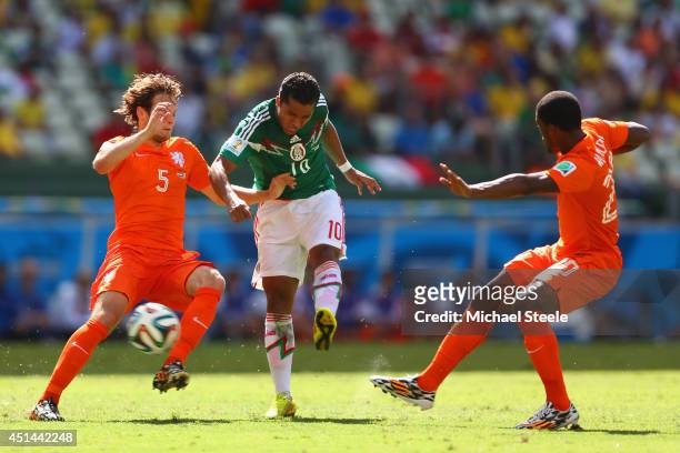 Giovani dos Santos of Mexico shoots and scores his team's first goal against Daley Blind and Georginio Wijnaldum of the Netherlands during the 2014...
