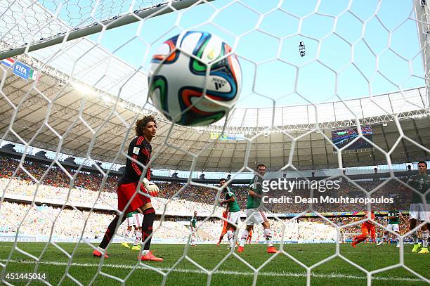 Wesley Sneijder of the Netherlands scores his team's first goal past Guillermo Ochoa of Mexico during the 2014 FIFA World Cup Brazil Round of 16...