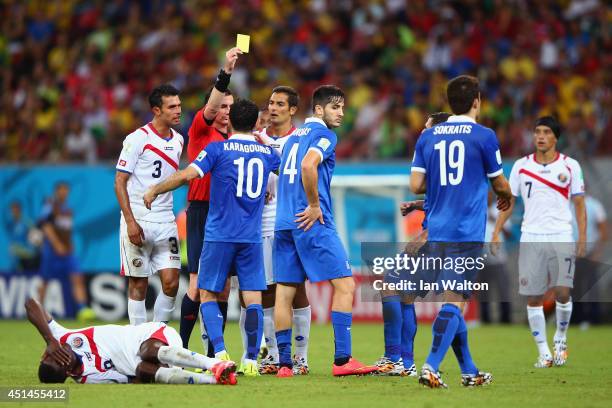 Konstantinos Manolas of Greece is shown a yellow card by referee Benjamin Williams after a challenge on Joel Campbell of Costa Rica during the 2014...